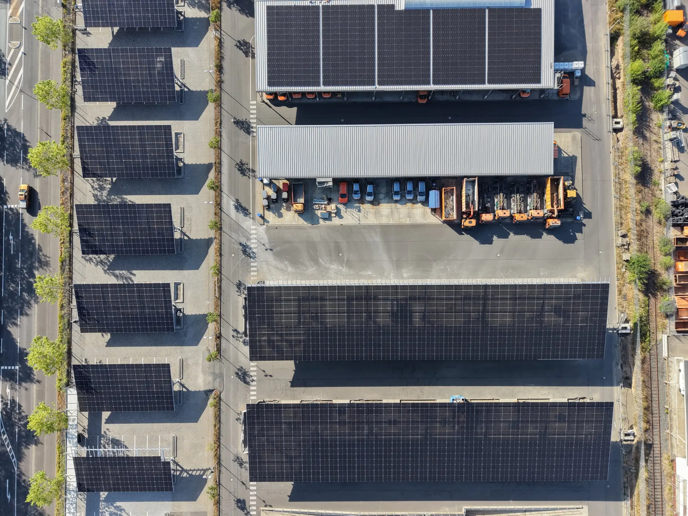 Zračni posnetek logističnega objekta s sončnimi nadstreški nad parkirišči in strešno elektrarno